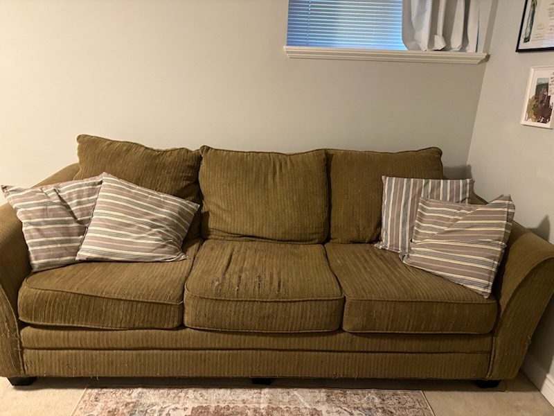 Green three-seat fabric couch with striped cushions ready for couch removal