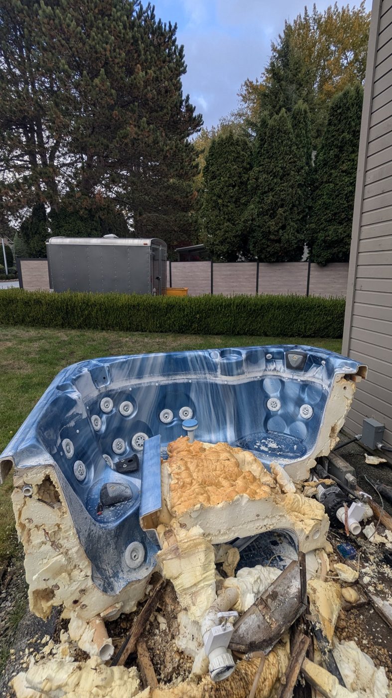Hot tub shell cut apart on the lawn with foam insulation and plumbing exposed during hot tub removal