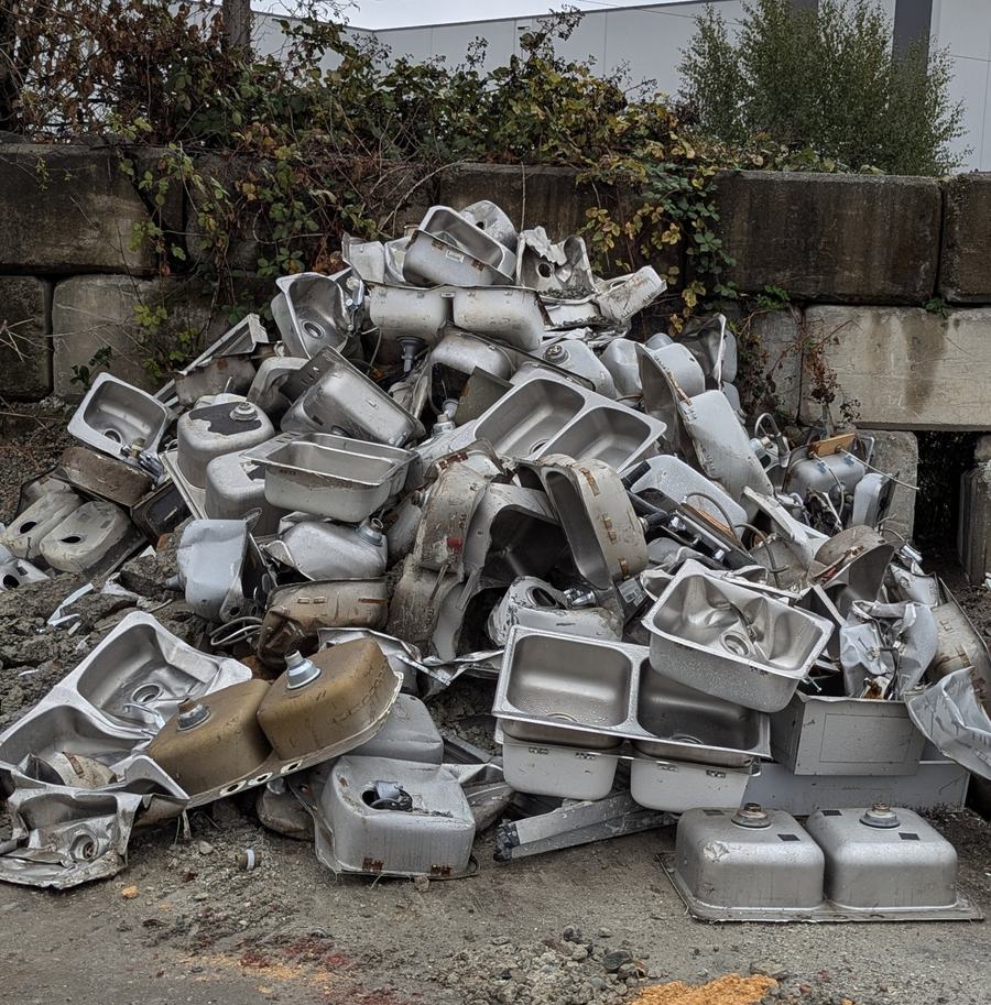 Pile of stainless steel sinks at a scrap metal yard collected for metal recycling